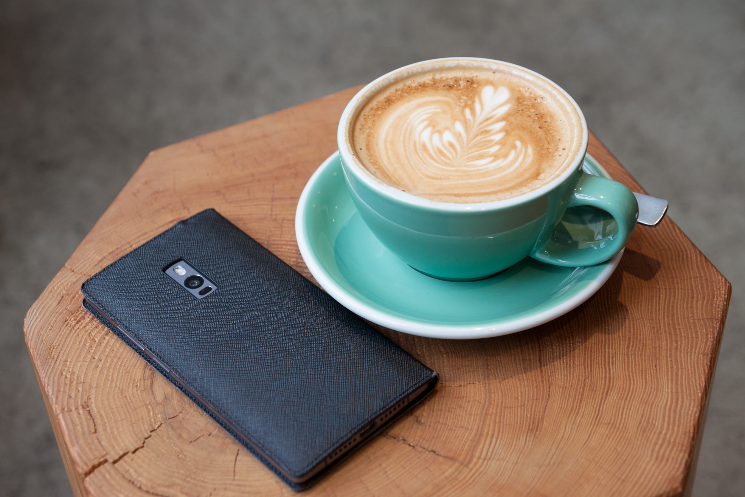 turquoise cup with a latte and cellphone