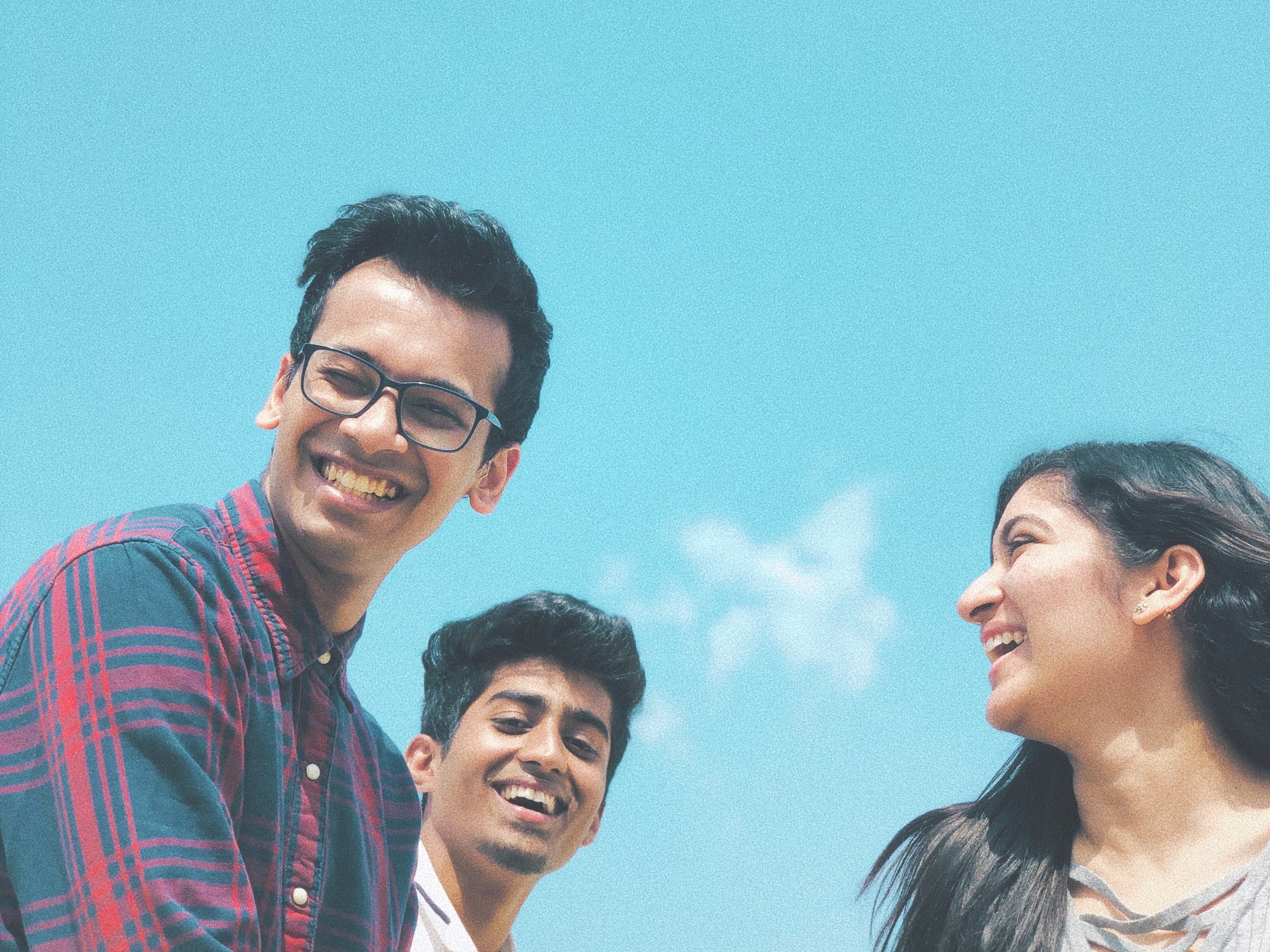 Three friends smiling under blue skies