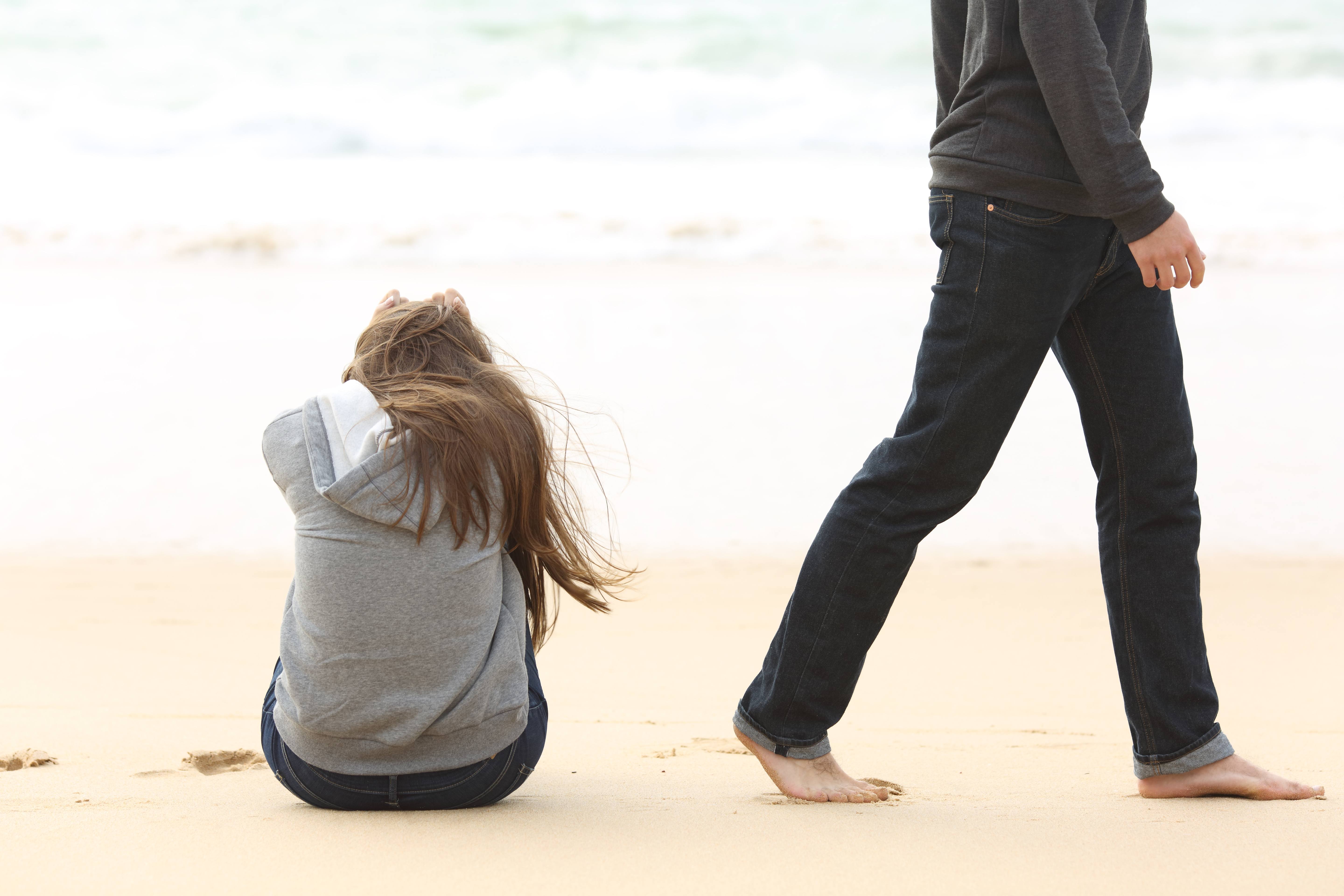 man walking away from sad wife on a beach