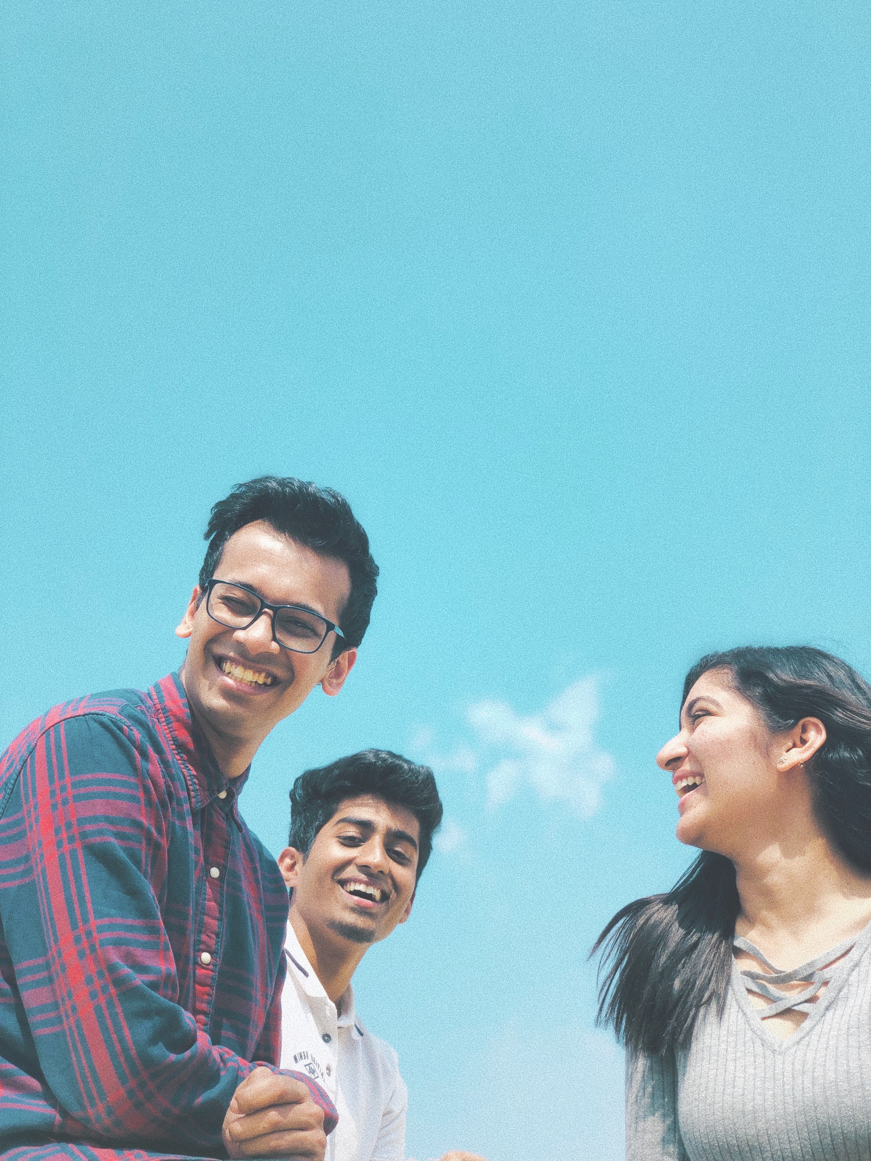 three friends smiling under blue skies